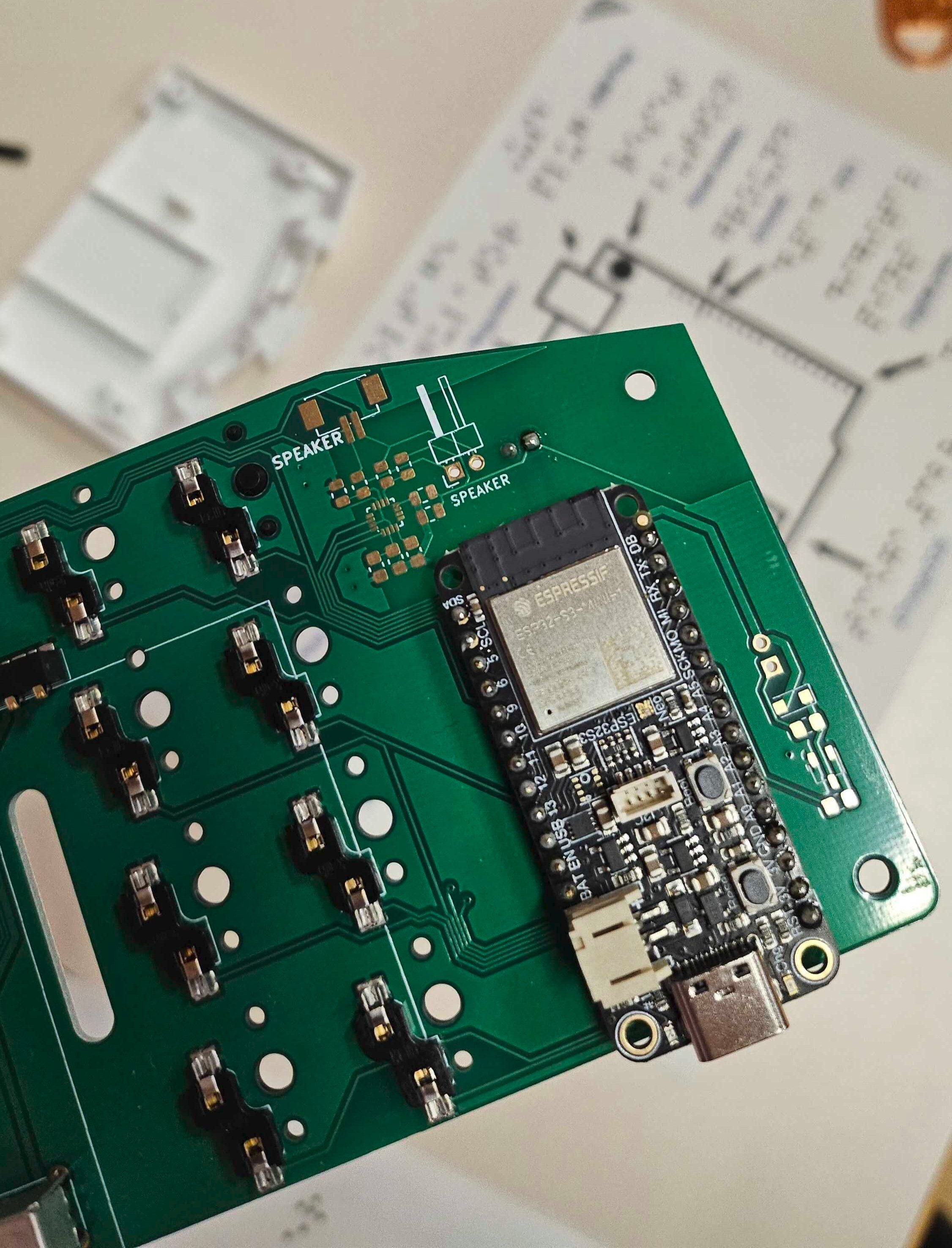 A green circuit board with an ESP32S3 processor on it. This processor is what translates the braille to latin alphabet before transmitting it to the device the keyboard is paired with.
